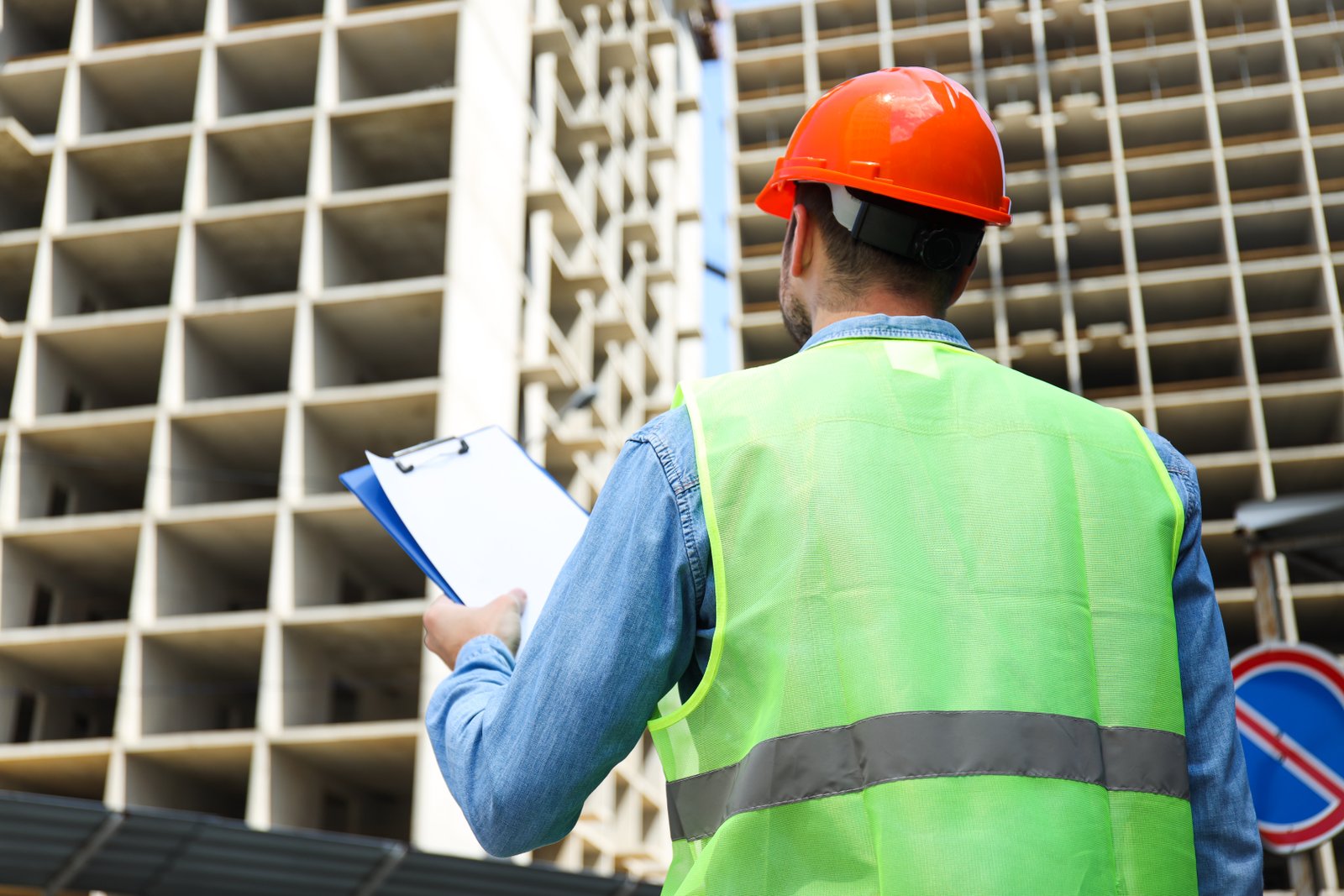 civil engineer safety hat with clipboard against construction